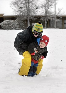 Three-year-old Kaston Beckett gets a snowboard ride from his cousin