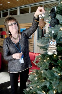 Sequim City Clerk Karen Kuznek-Reese places custom ornaments hand crafted by fourth-graders living within the Sequim School District upon the 9-foot-tall holiday tree in the lobby of the Sequim Civic Center.  Chris McDaniel/Peninsula Daily News
