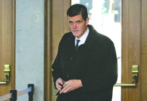 Washington state auditor Troy Kelley holds his wallet after showing his identification as he arrives for a federal court hearing Tuesday in Tacoma.  The Associated Press