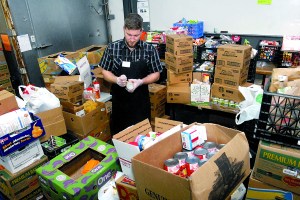 Port Angeles Food Bank warehouse manager Kevin Perry sorts through boxes of donated food