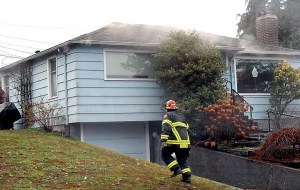 Port Angeles Fire Capt. Keith Bogues approaches a house at 808 E. 10th St. in Port Angeles after smoke was reported coming from under the eaves on Friday morning.  Keith Thorpe/Peninsula Daily News