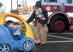 Three-year-old Evan Hernandez passes a can of donated food to Clallam County Fire District 2 emergency medical technician Teresa DeRousie during the “Fill the Fire Engine Food Drive” at the Lincoln Street Safeway grocery store in Port Angeles. Keith Thorpe/Peninsula Daily News