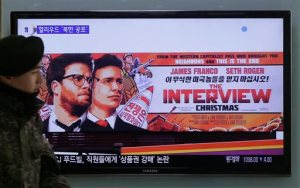 A South Korean army soldier walks near a TV screen showing an advertisement of Sony Pictures The Interview