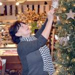 Debra Stuart, an employee at The Green Eyeshade, puts up some holiday decorations Thursday. (Mark Krulish/for Peninsula Daily News)