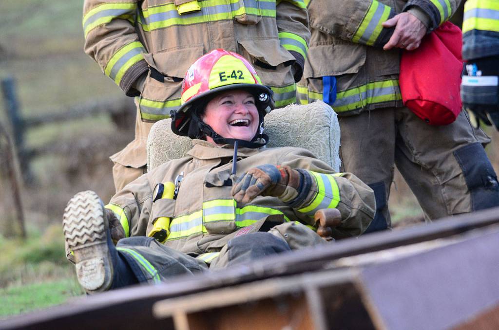 Vashina V Donnell, a firefighter for Clallam County Fire District No. 4, laughs while waiting for firefighters to start a house fire during the training day. (Jesse Major/Peninsula Daily News)
