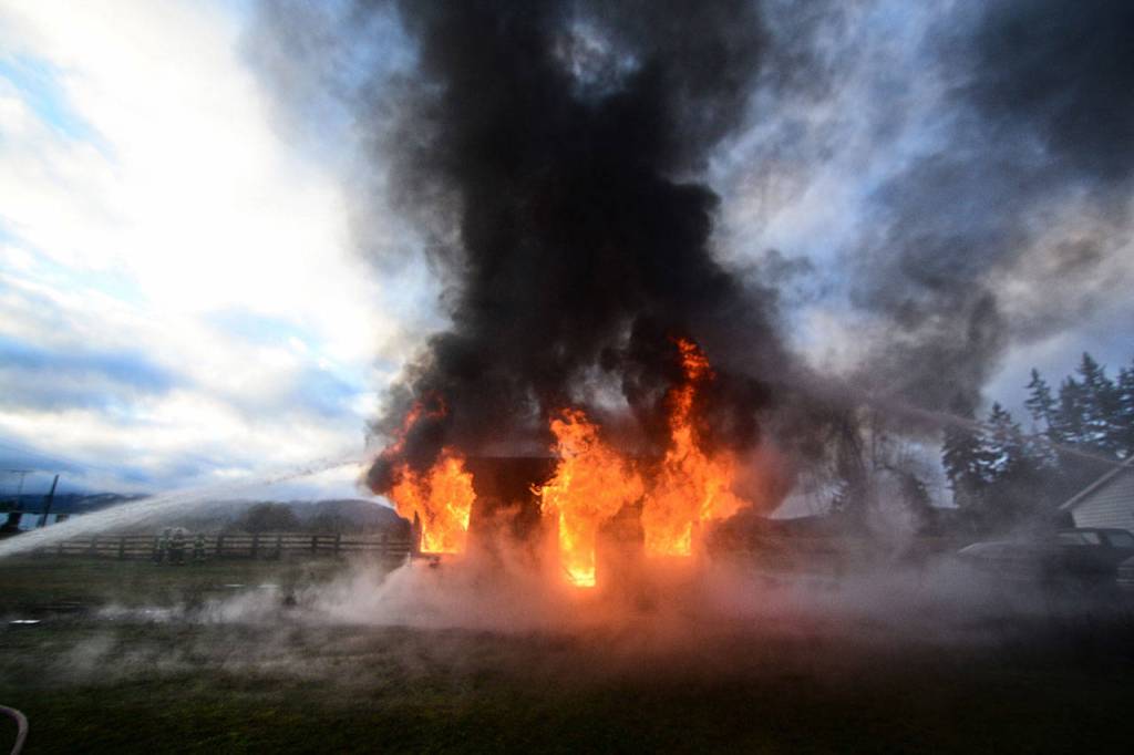 Smoke and flames pour out of a building that firefighters set on fire for training Sunday. (Jesse Major/Peninsula Daily News)