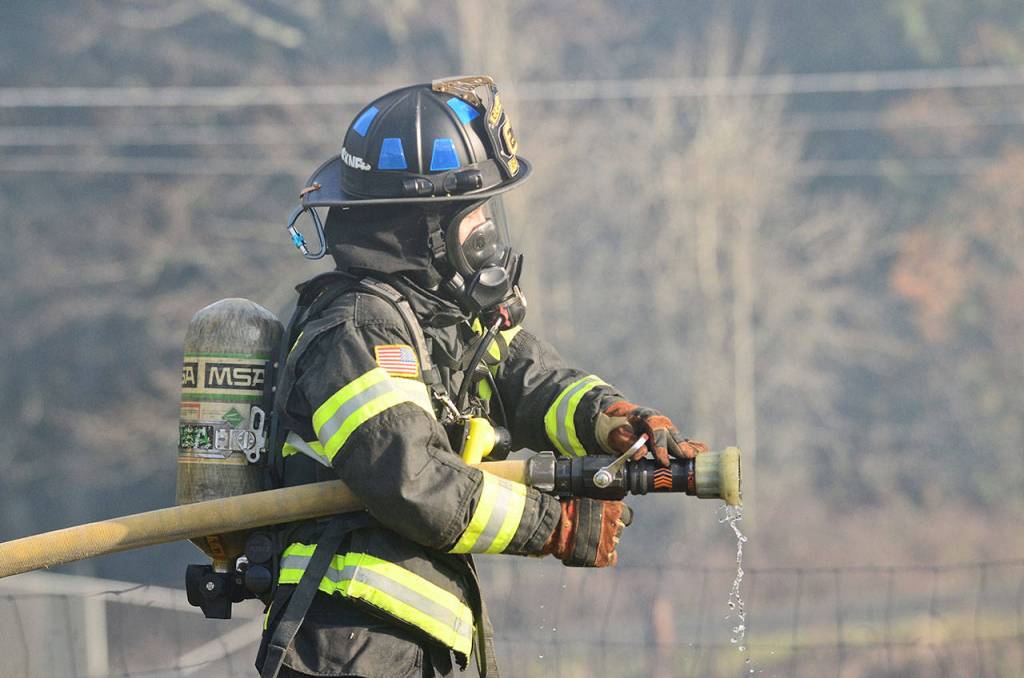 A firefighter prepares to enter a burning house during the training. (Jesse Major/Peninsula Daily News)