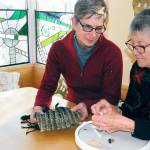 Weaver Cathie Wier, left, discusses Pat Herkals beaded embroidery piece for their collaboration. They will be part of the Chimacum Holiday Weekend on Saturday. (Jeannie McMacken/for Peninsula Daily News)