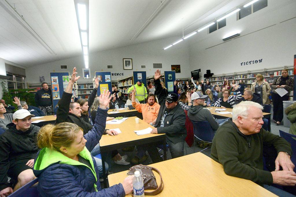 Parents raise their hands after a parent asked the crowd to raise their hands if they have a child who attends Chimacum High School who feels the administration is unfairly disciplining them during a parent forum Wednesday night at CHS. (Jesse Major/Peninsula Daily News)