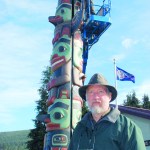 Woodcarver Dale Faulstich at the newly erected two-sided totem pole “Raven's Gift
