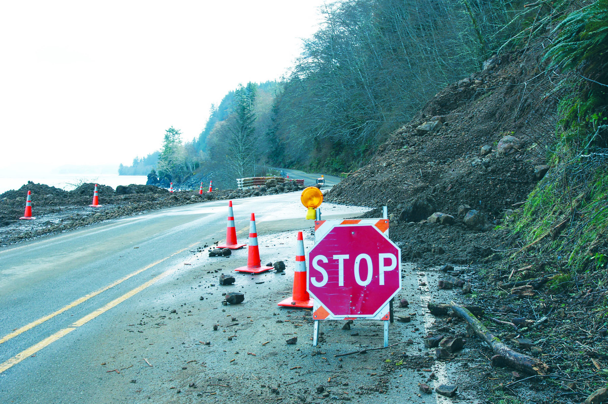 Traffic is allowed to negotiate around a 100-foot slide that hinders state Highway 112.  -- Photo by Brian Harmon/for Peninsula Daily News