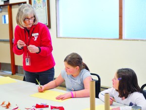 Longtime art instructor Cathy Haight helps Myra Walker and Sarah Howell with their mobiles during the Port Angeles YMCAs After the Bell program.  -- Photo by Chris Tucker/Peninsula Profile