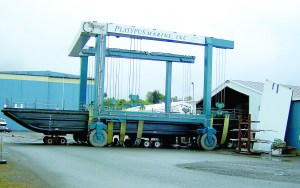 A huge Navy work barge sits in the slings of Platypus Marine Inc.s TraveLift as its carefully maneuvered out of a shop building and into the water.  -- Photo by David G. Sellars/for Peninsula Daily News