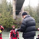 Operations coordinator John Hall gives instructions and data on Elwha River conditions Monday morning to kayakers from Clallam County Search and Rescue and the Sheriffs Office before they set out to look for a woman who apparently jumped from the bridge above and into the river over the weekend. (Paul Gottlieb/Peninsula Daily News)