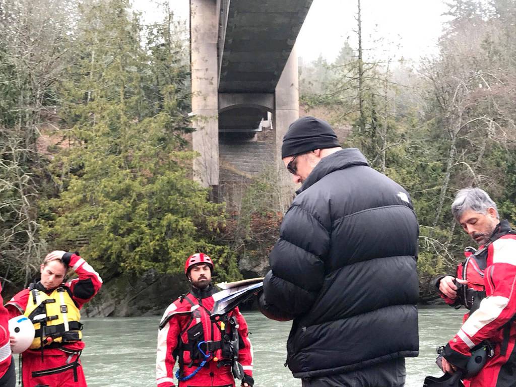 Operations coordinator John Hall gives instructions and data on Elwha River conditions Monday morning to kayakers from Clallam County Search and Rescue and the Sheriffs Office before they set out to look for a woman who apparently jumped from the bridge above and into the river over the weekend. (Paul Gottlieb/Peninsula Daily News)