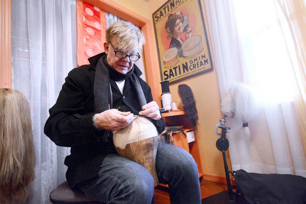 Michael Costain demonstrates how he makes wigs by hand. He said the process can take about three weeks, depending on the wig he is making. (Jesse Major/Peninsula Daily News)