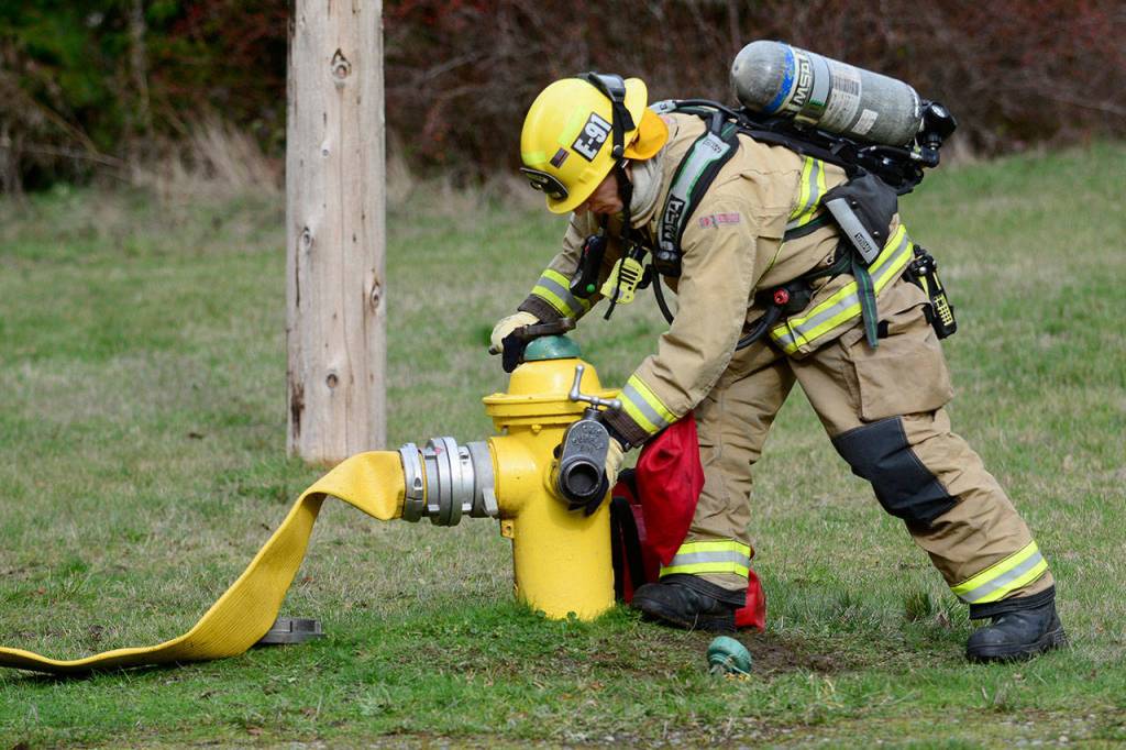Firefighter Alexander Chopski turns on a hydrant near the fire station at Naval Magazine Indian Island. (Jesse Major/Peninsula Daily News)