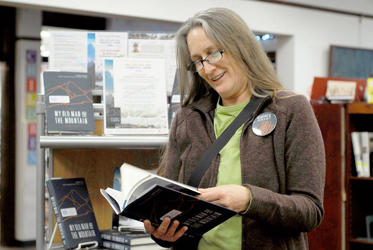 Cheryl Wallace of Port Townsend peruses a copy of Leif Whittakers My Old Man and the Mountain, this years Port Townsend Community Read selection, from the library display. Wallace said she heard Whittaker make a presentation in the past and believes the book will be as interesting and compelling as his talk. (Jeannie McMacken/for Peninsula Daily News)