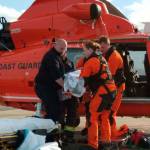 Members of a MH-65 Dolphin helicopter crew from Coast Guard Air Station/Sector Field Officer Port Angeles and emergency medical service personnel move an injured hiker to a stretcher on the air field at the air station Saturday. (Eric Mangiarelli, petty officer 3rd class/U.S. Coast Guard)