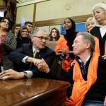Gov. Jay Inslee, center, shakes hands with Jim Parsons, lower right, of Bainbridge Island as Parsons wife, Ann-Marie, upper right, looks on, Tuesday after Inslee signed a measure into law that bans the sale and possession of bump stocks. The Parsons daughter Carrie was one of the victims of a mass shooting at a country music concert in Las Vegas in 2017. (Ted S. Warren/The Associated Press)
