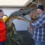 Sue and Tom Runyan with their dog Rufus stand by the familys decorative dinosaur, a velociraptor that theyve had in front of their Dungeness home for more than seven years. (Matthew Nash/Olympic Peninsula News Group)