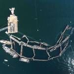In this Aug. 28, 2017, photo provided by the State Department of Natural Resources, a crane and boats are anchored next to a collapsed net pen used by Cooke Aquaculture Pacific to farm Atlantic Salmon near Cypress Island after a failure of the nets allowed tens of thousands of the nonnative fish to escape. (David Bergvall/Washington State Department of Natural Resources via AP)