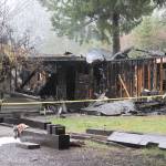 A fireman with District 1 Forks examines a structure that burned early Friday morning at 2300 Calawah Way outside the Forks city limits. (Lonnie Archibald for the Peninsula Daily News)