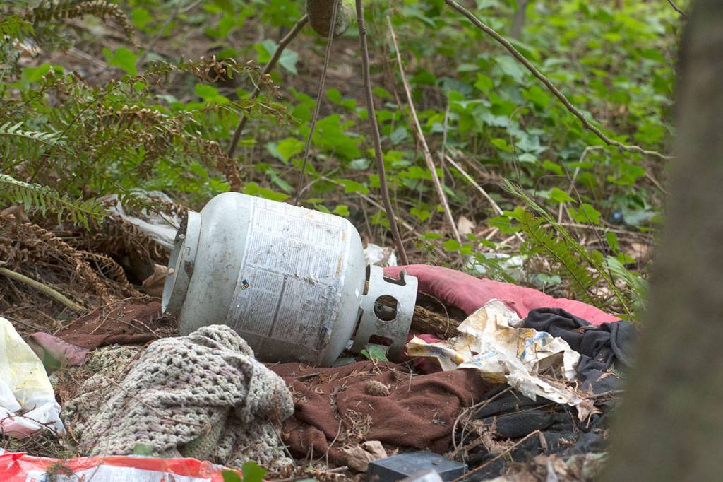 A propane tank sits in a pile of garbage along Valley Creek in Port Angeles on Wednesday. (Jesse Major/Peninsula Daily News)