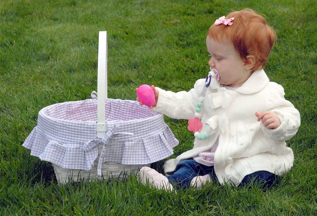 Rylie Marks, 11 months, looks over her basket of eggs she collected at the KONP Easter Egg Hunt at the Clallam County Fairgrounds on Saturday. (Keith Thorpe/Peninsula Daily News)