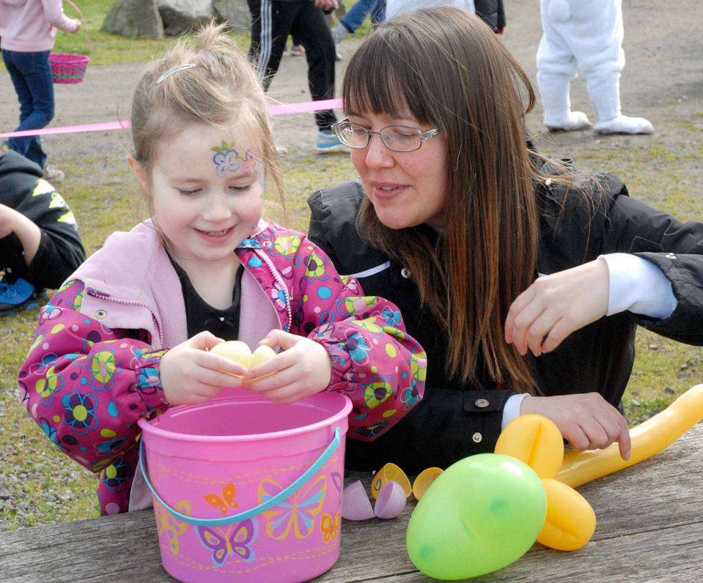 Lily Arrington, 7, opens plastic eggs as her mother, Melanie Arrington of Sequim, looks on at the conclusion of an Easter egg hunt at the Sequim Pumpkin Patch on Saturday. The Great 2018 Easter EGGstravaganza, hosted by community radio station KSQM, also featured prizes, pony rides, a bounce house and photo with the Easter bunny. (Keith Thorpe/Peninsula Daily News)