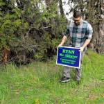 Candidate Ryan McAllister replaces one of his campaign signs that was stolen from a right of way in Brinnon. (Jeannie McMacken/Peninsula Daily News)