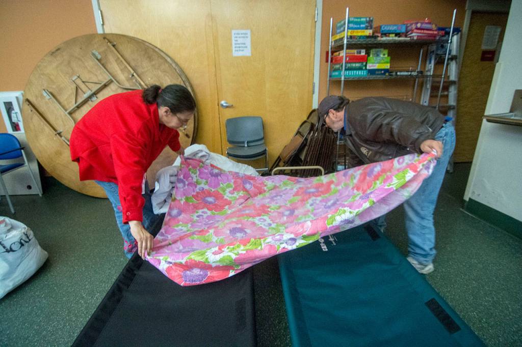 Amanda and Lewis Jones make their bed in Serenity House of Clallam Countys night-by-night shelter Tuesday night. The couple, which moved to Clallam County about nine months ago, has struggled to find housing since a tornado destroyed their Missouri home in 2011. (Jesse Major/Peninsula Daily News)