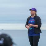 Carrie Sanford, who organized the Run Without Fear, stands atop a table as she tells a group of mostly women that the goal was to take back the Olympic Discovery Trail on Sunday. (Jesse Major/Peninsula Daily News)
