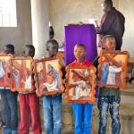Children from a church in Maralal, Kenya, hold paintings made by Jeanne Edwards to honor the 18-year-old who donated his heart to her husband, Mike Edwards.