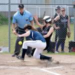 Quilcenes Kourtney Benek collides with Rainier Christian catcher, Kendra Dieber and scores a run in the 1B League Championship game in Quilcene on Friday. (Steve Mullensky/for Peninsula Daily News)