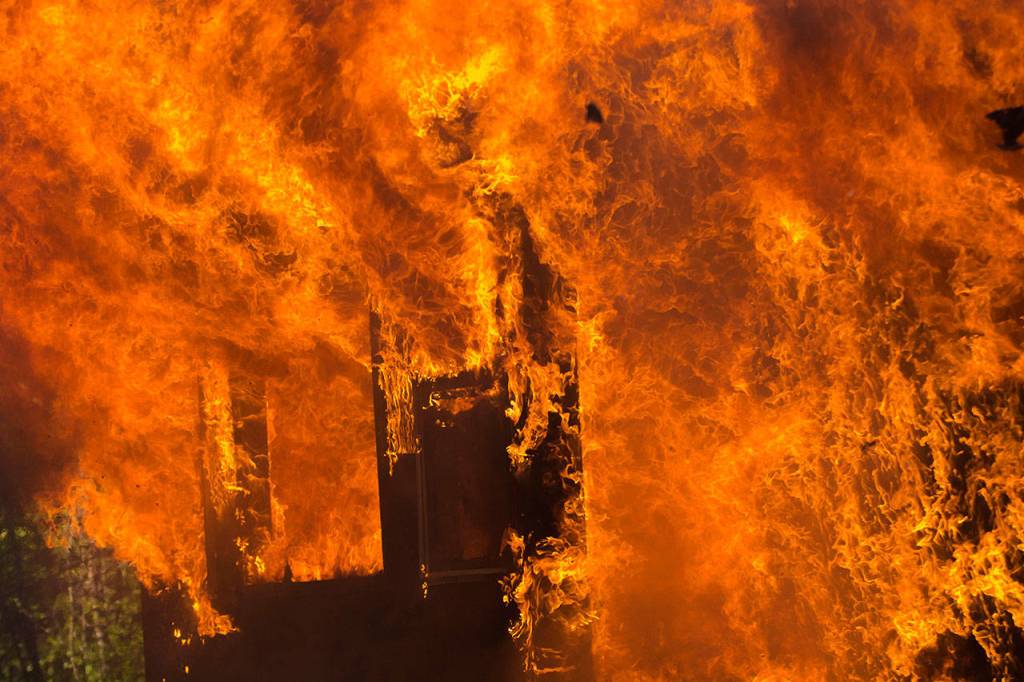 Flames shoot out of the home on Garling Road that was used for fire training. (Jesse Major/Peninsula Daily News)