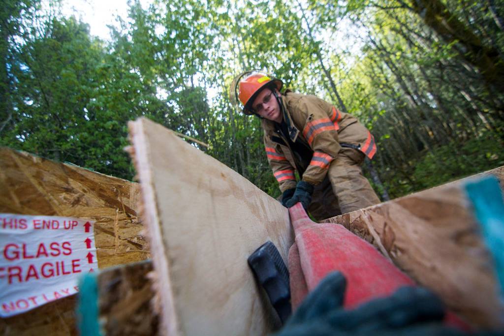 Fire Explorer Dakota Manley loads hose into a makeshift fire engine during the training. (Jesse Major/Peninsula Daily News)