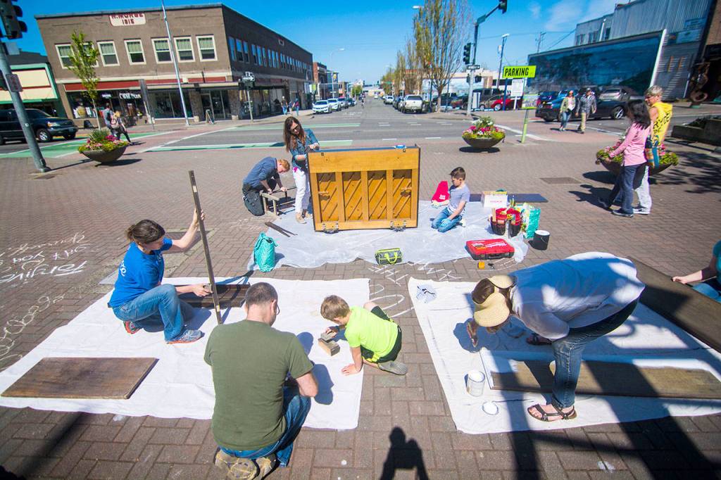 A work party on Saturday prepares Port Angeles downtown piano for a makeover on Saturday. (Jesse Major/Peninsula Daily News)