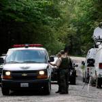 State Fish and Wildlife Police confer with an individual from the King County Medical Examiners office on a remote gravel road above Snoqualmie following a fatal cougar attack Saturday. (Alan Berner/The Seattle Times via AP)