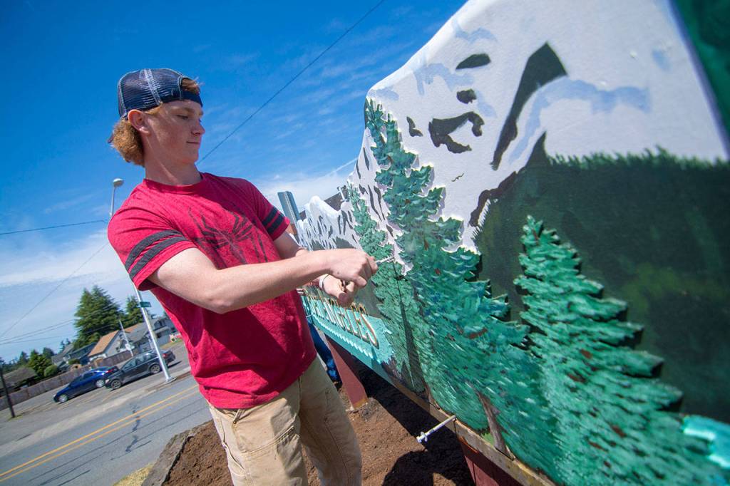 Port Angeles High School junior Glenn Deckart fastens the Welcome to Port Angeles sign he and others students made to posts on Thursday. (Jesse Major/Peninsula Daily News)