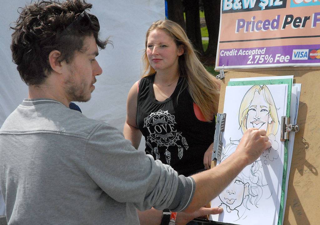 Caricaturist Patrick Ward of Seattle sketches Brittany Johnson of Port Angeles on Saturday outside the Vern Burton Community Center. (Keith Thorpe/Peninsula Daily News)