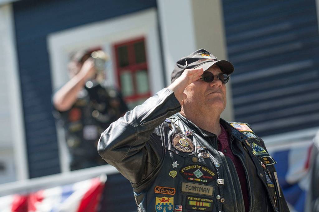 Norman Goodin salutes the American flag as it is raised at the Captain Joseph House Memorial service on Sunday. (Jesse Major/Peninsula Daily News)