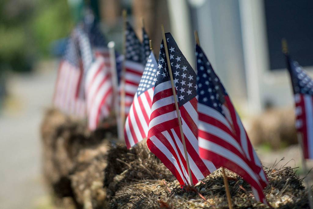 American flags line bales of straw at the Captain Joseph House Memorail Service on Sunday. (Jesse Major/Peninsula Daily News)