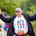 Douglas Atterbury, participating in the seventh annual Run for Joe in support of the Captain Joseph House Foundation, crosses the fnish line at the North Olympic Discovery Marathon on Sunday. (Jesse Major/Peninsula Daily News)