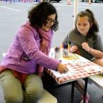 Stephanie Brooks, YMCA Jefferson County Snap-Ed coordinator, plays Veggie Bingo with 7-year-old Jaxzen Berg of Port Townsend at the new location of the Wednesday Farmers Market at the Haines Street Park and Ride Transit Center. (Jeannie McMacken/Peninsula Daily News)