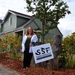 Laraine Claire stands outside her home on the corner of Spruce Street and Fourth Avenue where volunteers helped paint and revitalize her home. She said the project helped inspire hope in her. (Matthew Nash/Olympic Peninsula News Group)