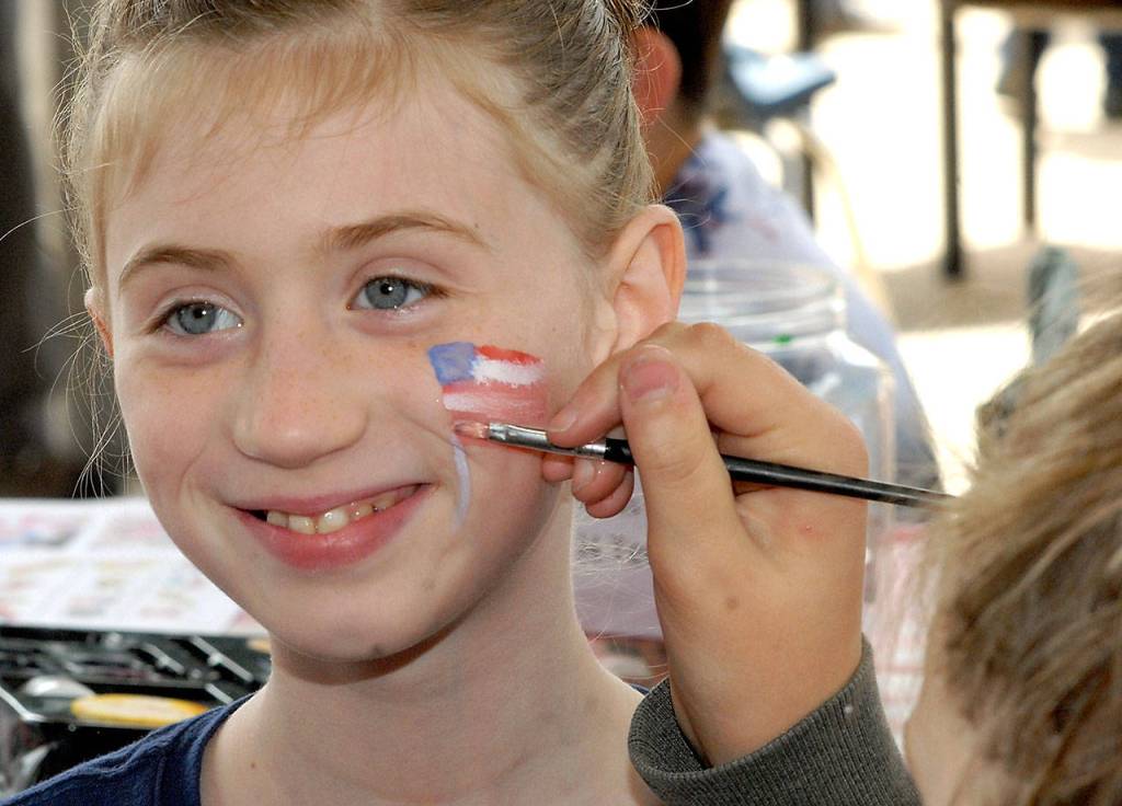 Ten-year-old Makenzy Thompson of Port Angeles receives an American Flag from face painter Abby Sanford in honor of Independence Day at the childrens activity area in the pavillion at The Gateway transit center in Port Angeles on Wednesday. (Keith Thorpe/Peninsula Daily News)