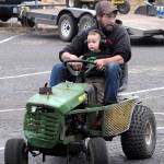 Adam Coile of Port Townsend rides a souped-up lawn mower with his son, Christopher Cole, 1 1/2, during warm-ups for Wednesdays mower races in Port Angeles. (Keith Thorpe/Peninsula Daily News)