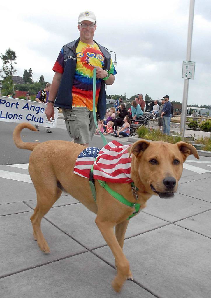 Eric Bjork walks with his dog Gordon with a parade entry from the Port Angeles Lions Club. (Keith Thorpe/Peninsula Daily News)