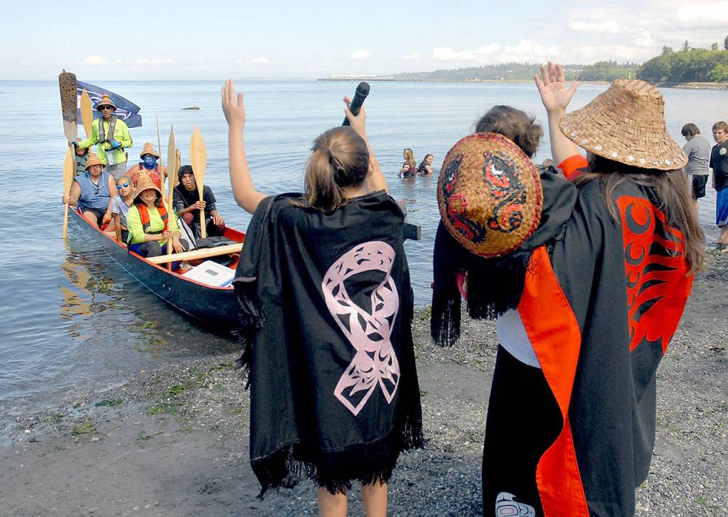 A canoe representing Sechelt First Nation of British Columbia is greeted by Lower Elwha Clallam tribal members, from left, Malena Marquez, 11, Emma Marquez, 1, and Wendy Sampson. (Keith Thorpe/Peninsula Daily News)